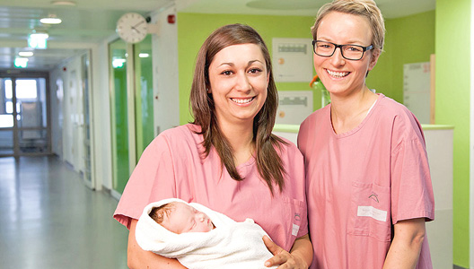 Zwei Schwestern der Geburtshilfestation des Donau Isar Klinikums Deggendorf mit einem Baby