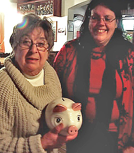 Roswitha Schröder überreicht ein Sparschwein an Linda Nowak
