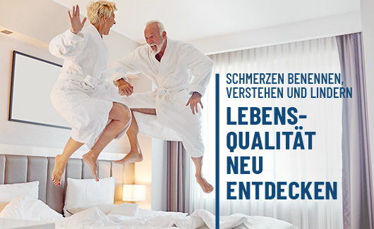 Paar springt ausgelassen auf Hotelbett